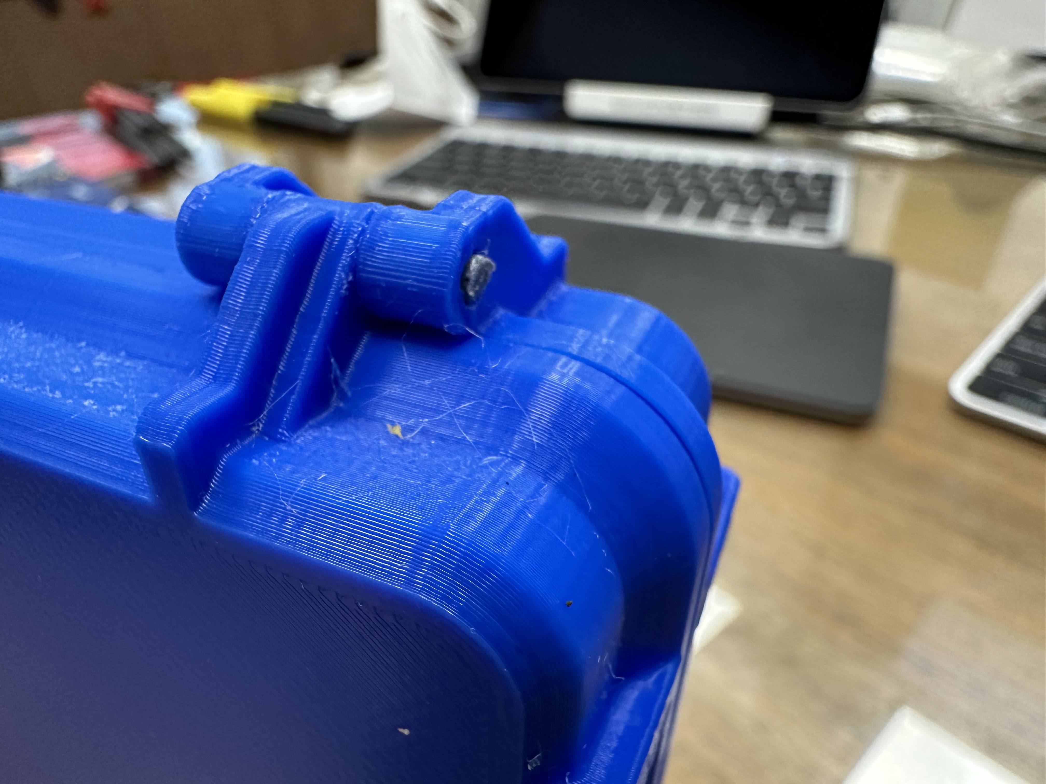 A closeup of the case hinge showing some wispy bits of PLA.